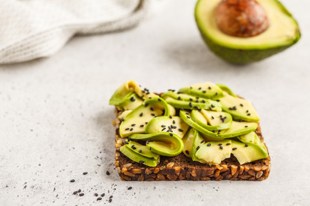Avocado toast on a healthy sesame bread with sesame seeds on white background, copy space. Healthy vegan food concept.の写真素材
