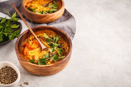 Yellow Indian vegan lentil soup curry in a wooden bowl, white background, top view.の写真素材