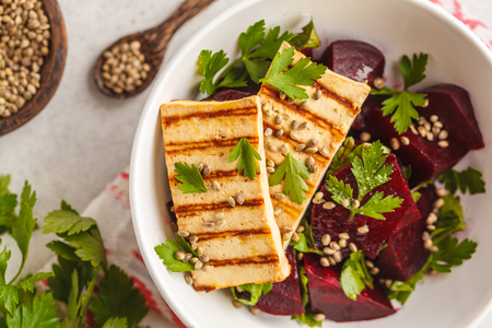 Baked beet salad with grilled tofu parsley and oil in a white bowl. Healthy vegan food concept.の写真素材