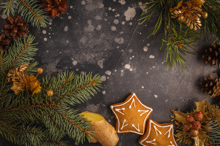 Traditional Christmas gingerbread star cookies in Christmas decorations. Dark background, top view.