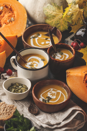 Autumn pumpkin soup puree with cream in cups, the autumn scenery. Healthy vegan food concept. Autumn food concept.の写真素材