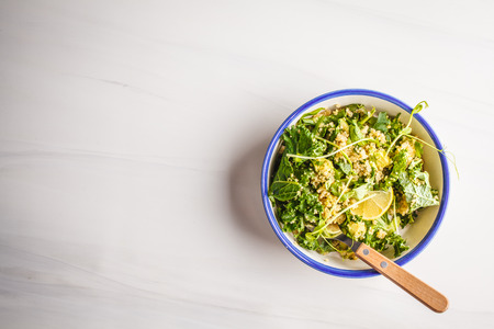 Kale, quinoa, avocado vegan salad in a white bowl on a white background. Plant based diet concept.の写真素材