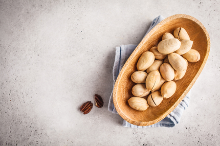 Pecan nuts in a wooden bowl on a white background. Plant based diet concept.の写真素材
