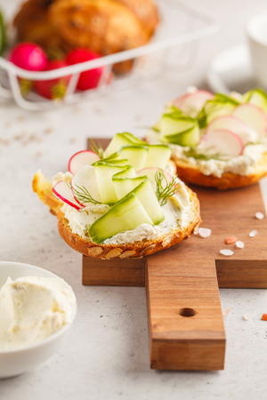 Breakfast cream cheese, cucumber and radish sandwiches on a wooden board. Clean eating food concept.の写真素材