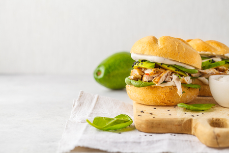 Grilled chicken and avocado burger on wooden board. Healthy food concept.の写真素材