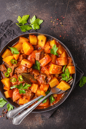 Beef stewed with potatoes in tomato sauce. Meat traditional goulash, top view, copy space.の写真素材