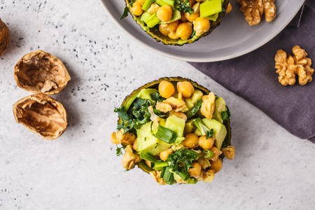 Avocado halves stuffed with avocado, nuts and chickpeas. Plant based diet concept, copy space.の写真素材