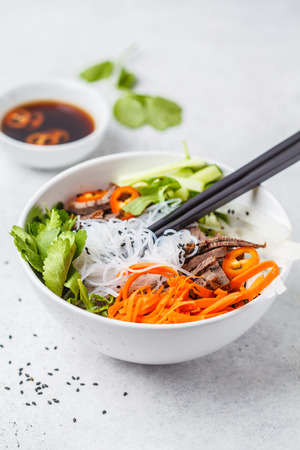 Bun cha salad bowl. Vietnamese rice noodle with beef and chilli vegetables salad in white bowl, top view.の写真素材