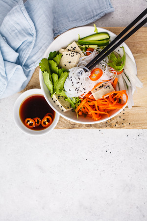 Vietnamese rice noodle with tofu and chilli vegetables salad in white bowl, top view, copy space.の写真素材