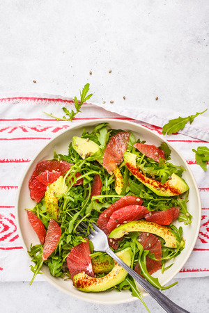Avocado and grapefruit salad in a white plate on a white background, top view.の写真素材