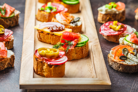 Assorted spanish tapas with fish, sausage, cheese and vegetables. Dark background, flat lay.の写真素材