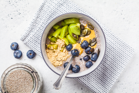 Vegan breakfast. Chia pudding with kiwi, blueberries and peanut butter in a gray bowl.の写真素材