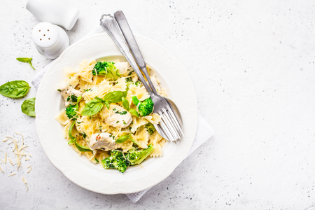 Italian pasta farfalle with broccoli, chicken and cheese in a white plate. White background, top view.の写真素材