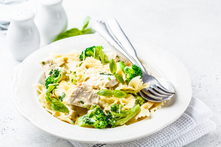 Italian pasta farfalle with broccoli, chicken and cheese in a white plate. White backgroundの写真素材
