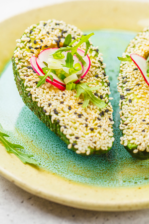 Beautifully decorated avocado with sesame, arugula, radish and green onions.の写真素材