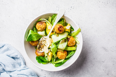 Vegan salad with beans meatballs, avocado and cucumber in white plate on a white background.の写真素材