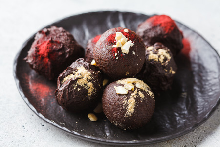 Healthy raw vegan energy balls with cocoa, dates, maca, chia on white background.