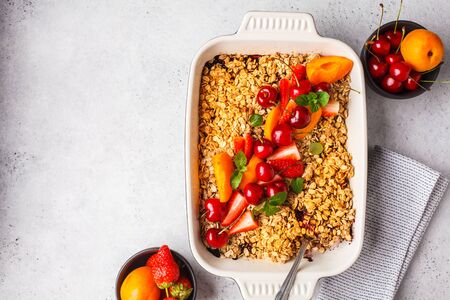 Fruits and berries oat crumble in oven dish on a gray background, copy space.の写真素材