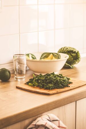Cooking green vegan salad from kale and avocado in the kitchen.の写真素材
