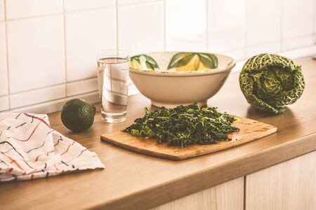 Cooking green vegan salad from kale and avocado in the kitchen.