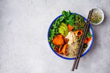 Healthy vegan lunch in a white bowl. Buddha bowl with avocados, sweet potatoes, sprouts and...