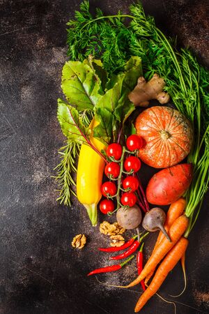 Autumn vegetables background. Pumpkin, zucchini, sweet potatoes, carrots and beets on a dark background.の写真素材