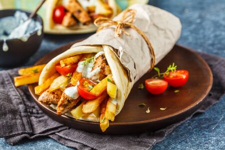 Gyros souvlaki wraps in pita bread with chicken, potatoes and tzatziki sauce, blue background.の写真素材
