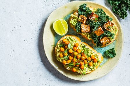 Vegan open sandwiches with guacamole, tofu, chickpeas and sprouts on a plate. Healthy vegan food concept.の写真素材