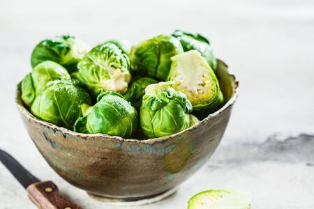 Raw brussels sprouts in a bowl, gray concrete background. Healthy vegan food concept.の写真素材