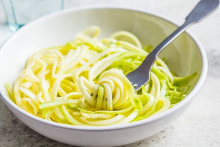 Zucchini pasta in a white plate. Raw vegan food concept.の写真素材