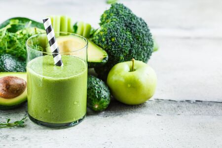 Green broccoli, avocado, spinach, apple smoothie in a glass and ingredients for smoothie background.の写真素材