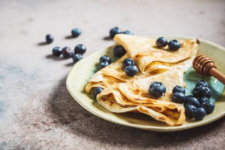 Thin sweet crepe pancakes with blueberries and honey.