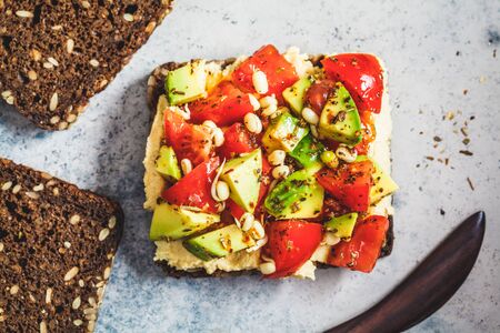 Avocado, tomato and hummus toast with seedlings. Healthy vegan food concept.の写真素材