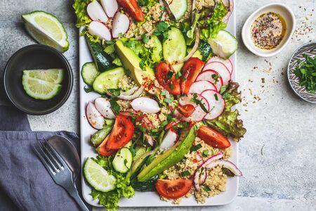 Quinoa salad with tomato, cucumber, radish and avocado on a gray rectangular plate. Healthy vegan food concept.の写真素材