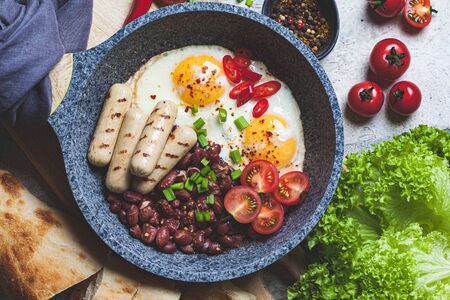 Fried eggs, sausages and beans - breakfast in a pan. Homemade breakfast concept.の写真素材