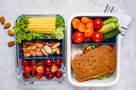 Lunch box with healthy fresh food. Sandwich, vegetables, fruits and nuts in a food container, white background.の写真素材