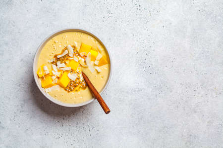 Tropical mango and coconut smoothie bowl, light background, copy space.の写真素材