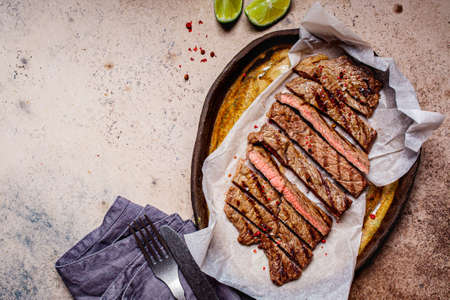 Sliced grilled beef steak with spices in a dark dish, dark background.の写真素材
