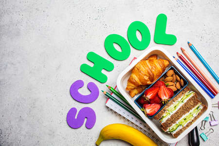 Back to school concept. Lunch box with a sandwich, croissants and snacks for school. School background with the inscription - school.の写真素材