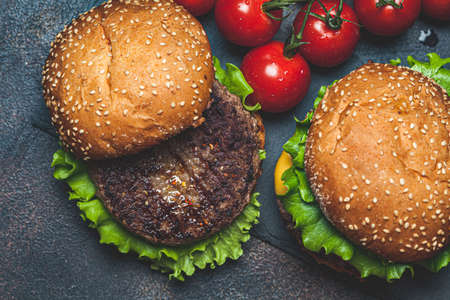 Homemade burgers with beef cutlet, cheese and vegetables, a dark background, top view.の写真素材