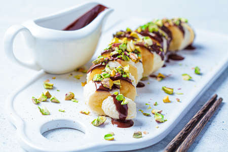 Sweet banana sushi with chocolate and nut, white background. Vegan dessert concept.