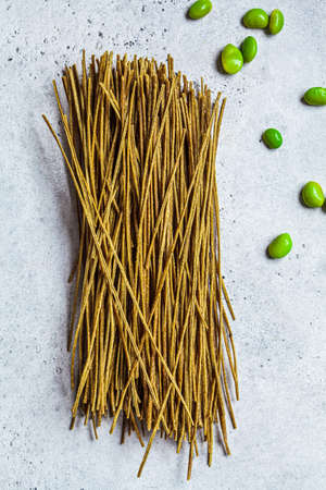 Raw green vegan edamame noodles on gray background. Plant based food concept.