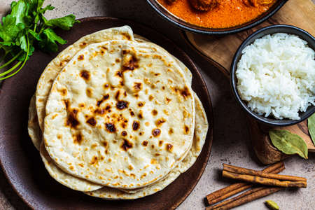 Chapati bread on a wooden plate, top view. Indian cuisine concept.