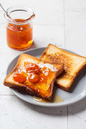 Toast with butter and apricot jam on a gray plate. Breakfast food concept.