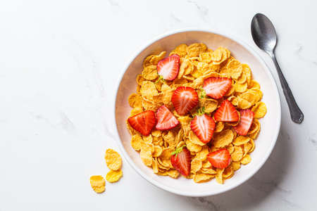 Cornflakes cereals with strawberries in a white bowl, top view. Healthy breakfast concept.の写真素材