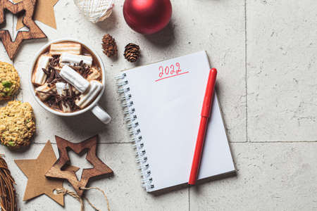 Christmas or New Year festive background. Hot chocolate or cocoa with marshmallow in white cup, cookies, notebook, christmas decorations, top view, copy space, gray tiles background.の写真素材