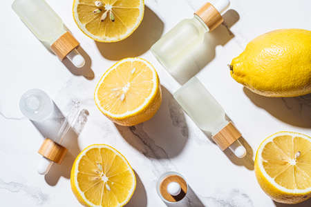 Lemon essential oil in glass bottles, white marble background, top view. Skin and body care concept.の写真素材