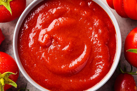 Homemade tomato sauce in a gray bowl, top view. Cooking from summer vegetables concept.の写真素材