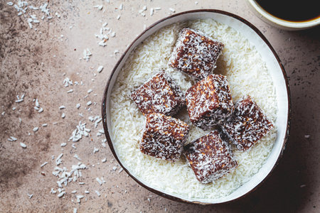 Vegan coconut and dates energy squares in a coconut bowl, top view.