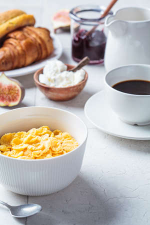 Breakfast table with cornflakes, croissants and a cup of coffee. Gray tile background, copy space, close-up.の写真素材